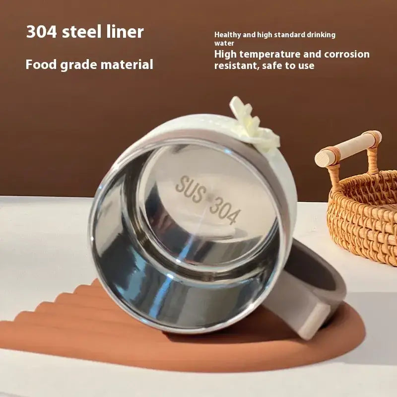 Shiny stainless steel mug with a white handle and decorative bow.