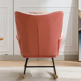 A soft coral-colored upholstered rocking chair with a sleek black metal frame and wooden rockers.