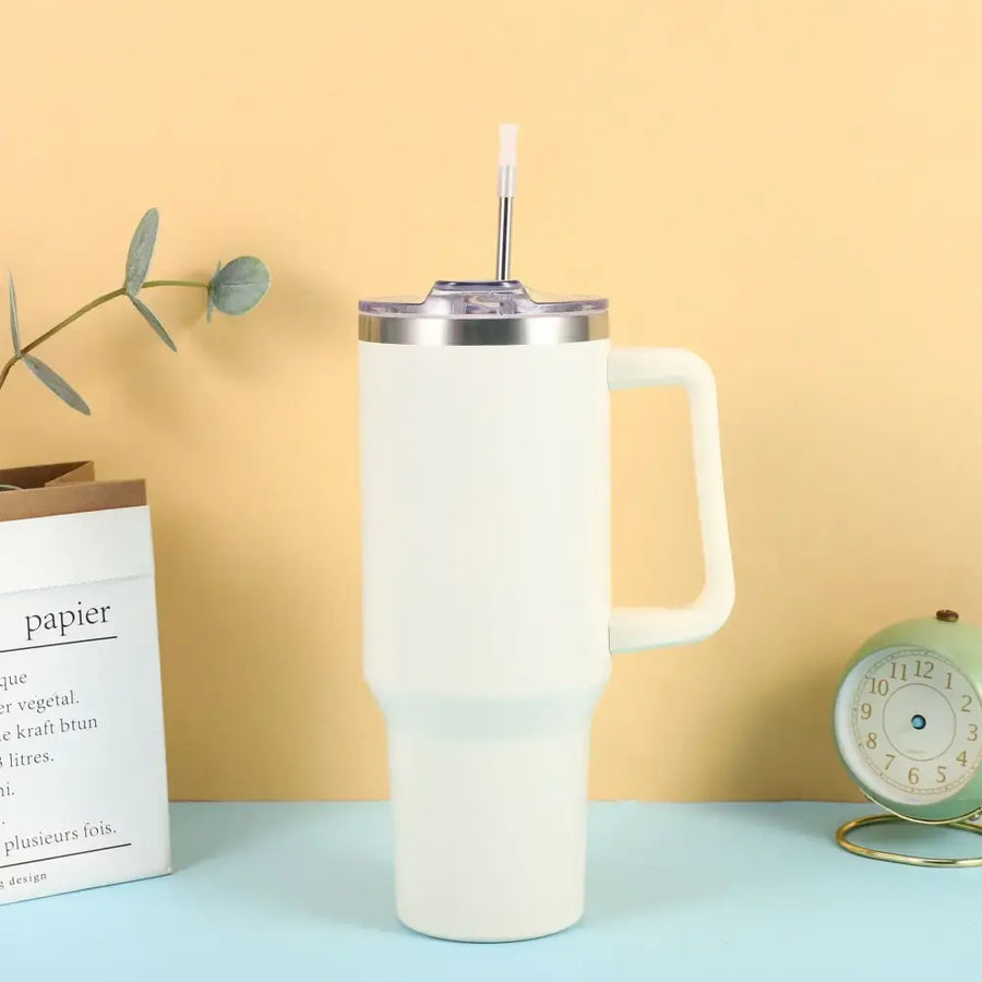 Cream-colored insulated tumbler with a stainless steel rim, clear lid, and integrated handle.