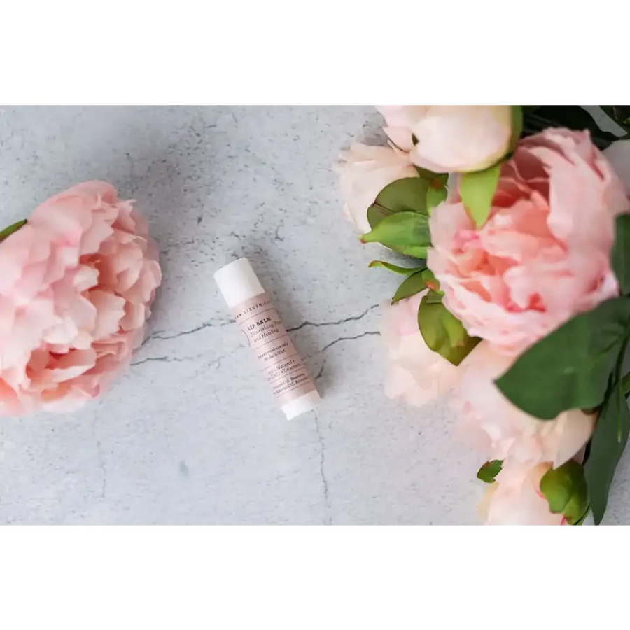 A sleek, minimalist pink lip balm tube with a white cap and elegant gold lettering.