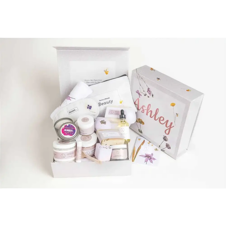 White gift box with floral illustrations and the name ’ashley’ in pink cursive script, containing an assortment of beauty products.