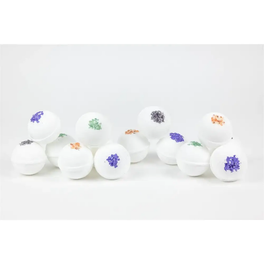 White spherical bath bombs with colorful, glittery floral toppings in shades of purple, green, and orange.