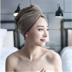 A soft, beige microfiber towel wrapped neatly around a woman’s head.