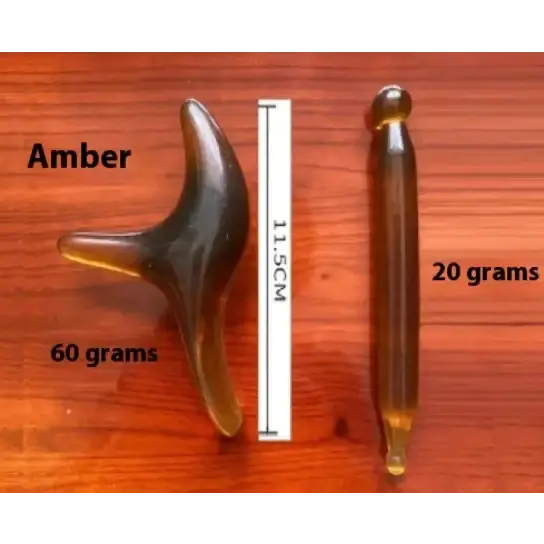 A polished amber massage tool with a curved, three-pronged design and a smooth, translucent golden-brown finish.