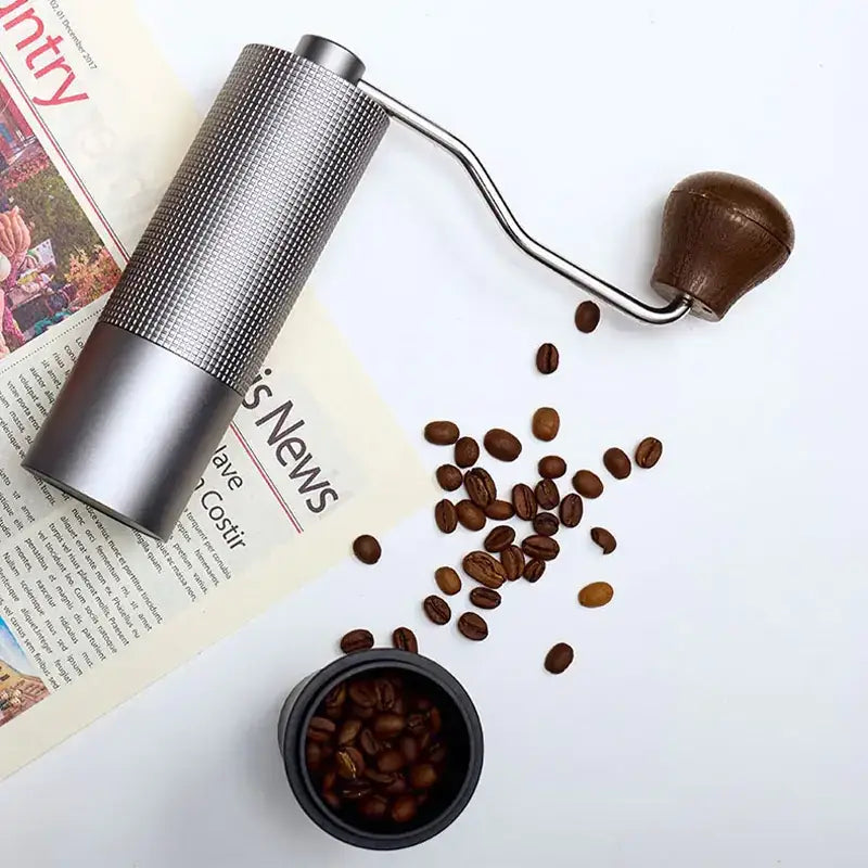 Silver metallic manual coffee grinder with a textured grip and a dark brown wooden handle.