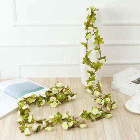 A delicate white and green artificial flower vine with realistic petals and leaves, designed for decorative use.