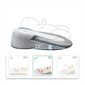 Gray wedge-shaped baby sleep positioner with a soft, cushioned surface designed to support an infant at a 15-degree incline.