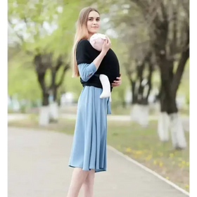Black fabric baby carrier with light blue sleeves and matching skirt-like panel, holding a swaddled infant.