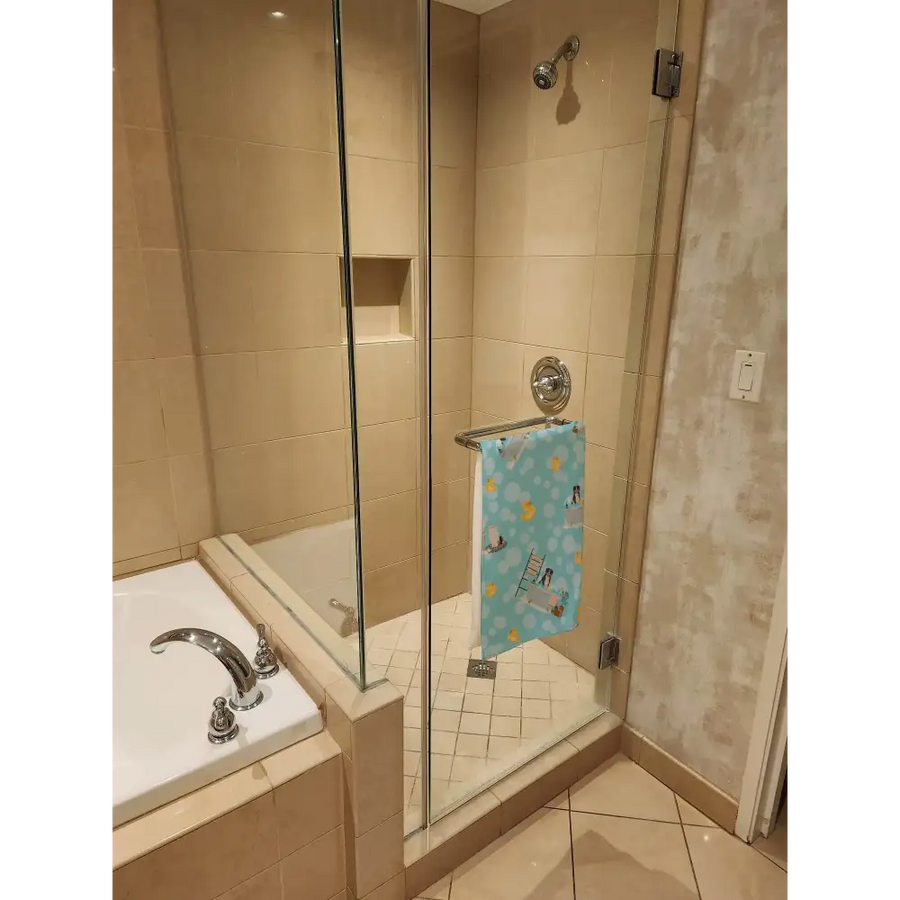 Light blue towel with yellow duck and ladder patterns hanging on a chrome shower rod.