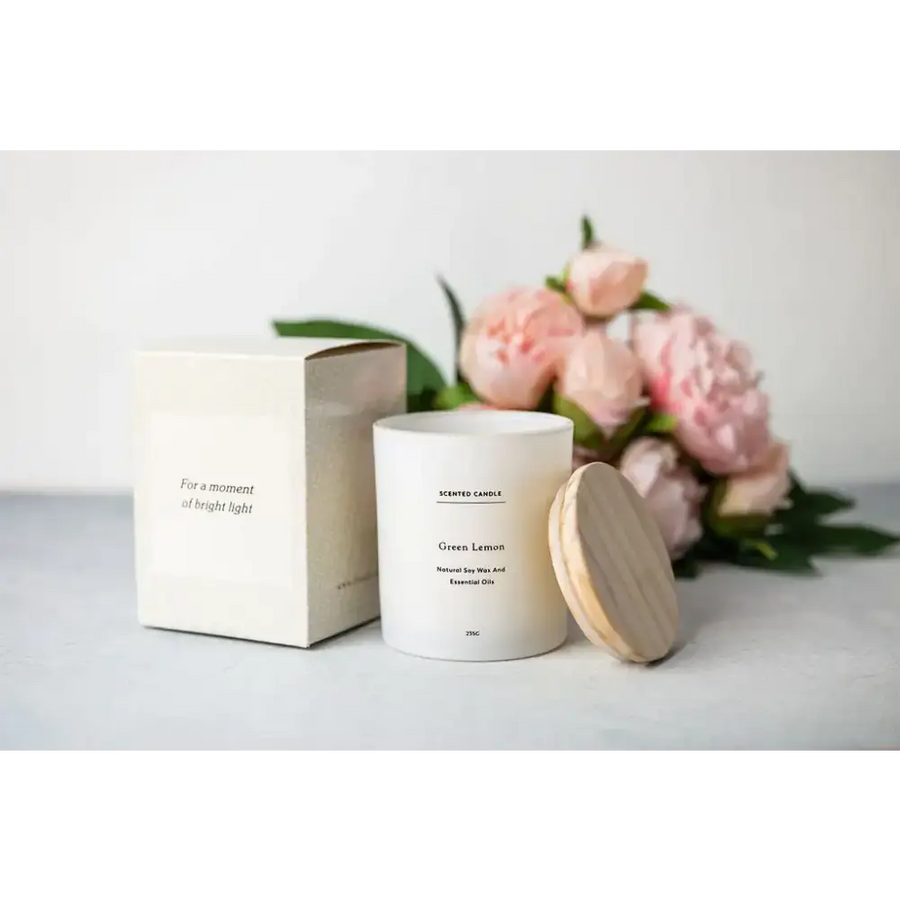 White cylindrical scented candle with a wooden lid, labeled ’green lemon’ and made of natural soy wax.