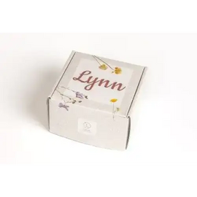 A white cardboard box with a delicate floral design and the name ’lynn’ printed in elegant cursive script.