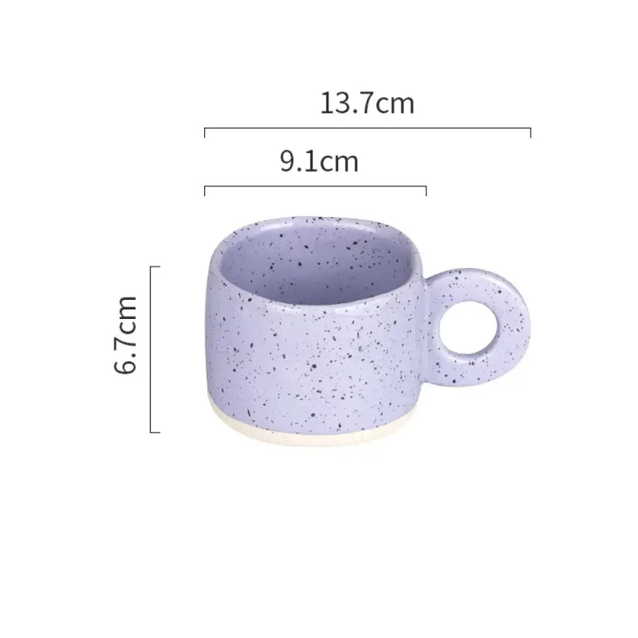 A lavender speckled ceramic mug with a circular handle and white base.