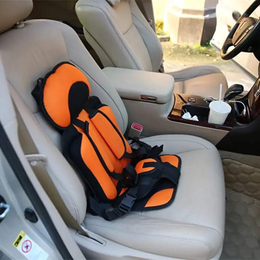 Bright orange and black child safety seat with padded headrest and adjustable straps, designed for secure car travel.