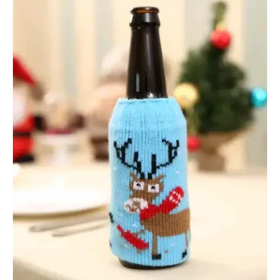 A light blue knitted bottle sleeve featuring a brown reindeer with antlers, holding red mittens and carrots.