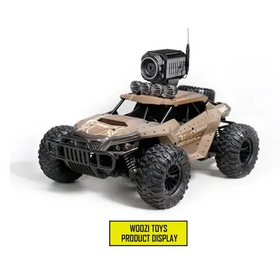 Tan and black remote-controlled off-road vehicle with rugged tires, a mounted camera on the roof, and tactical detailing.