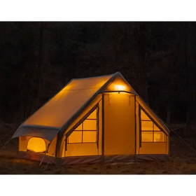 A warmly lit, beige canvas tent with a triangular roof and multiple windows.