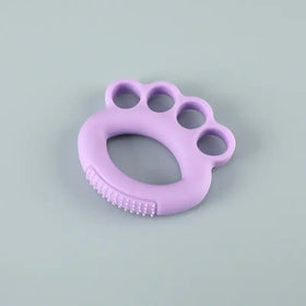 Purple silicone baby teether shaped like a paw with textured ridges along the bottom edge.
