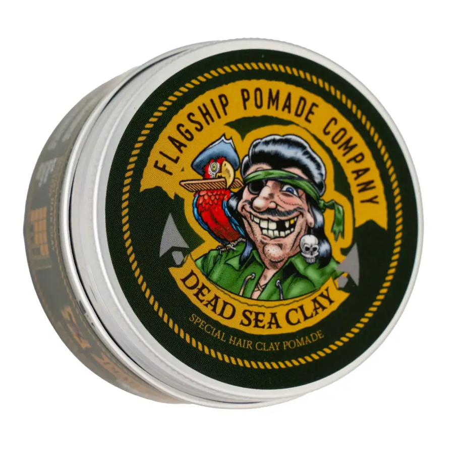 A round, silver tin of flagship pomade company’s dead sea clay pomade featuring a cartoon pirate with a parrot and skull design on its label.