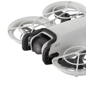 White and black drone with protective cage design, featuring a mounted camera lens.