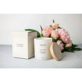 White cylindrical scented candle with a wooden lid, labeled ’green lemon’ and made of natural soy wax.