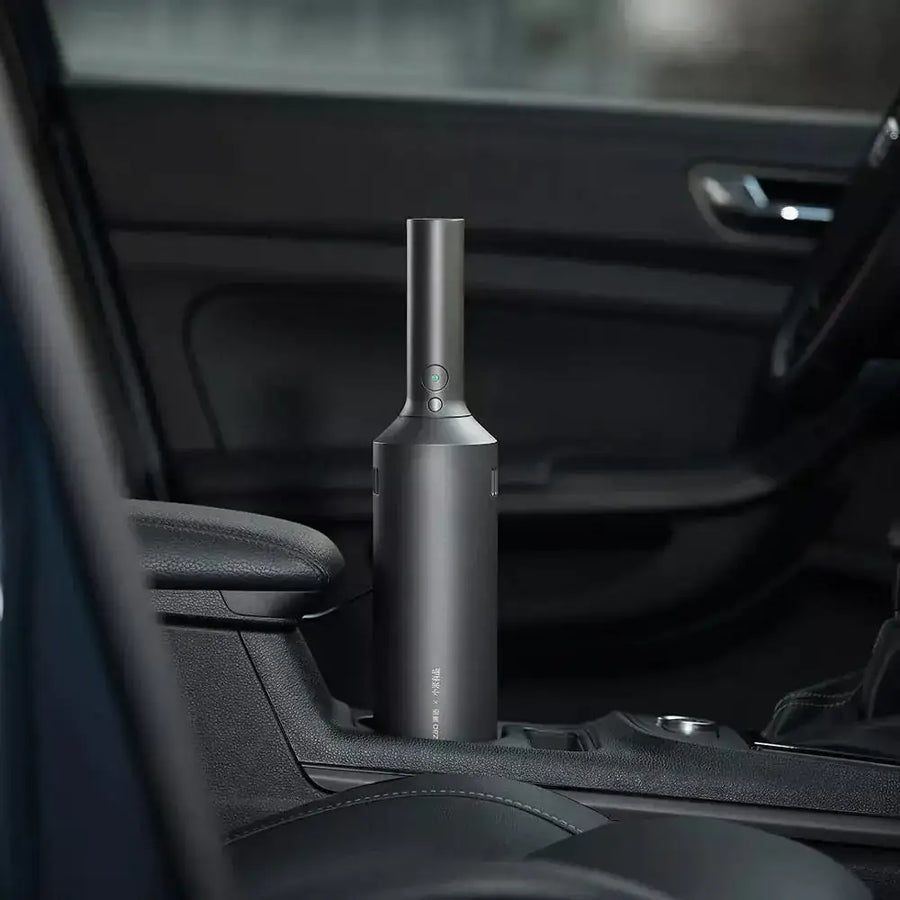 A sleek, matte black handheld car vacuum with a cylindrical body and a narrow nozzle.