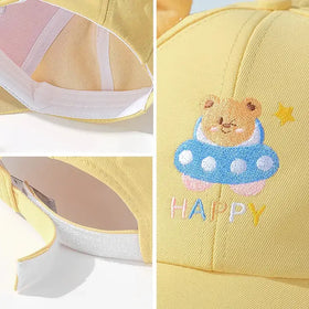 Yellow baseball cap featuring a cute embroidered bear in a blue ufo with white polka dots, accompanied by the word ’happy’ and a small star.