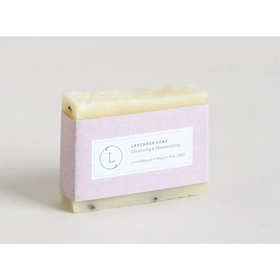 A rectangular bar of pale lavender soap with a subtle speckled texture, wrapped in light purple paper featuring a minimalist label.