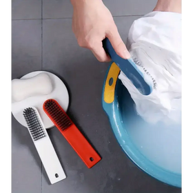 Blue and yellow scrub brush with a curved handle being used to clean white fabric in a blue basin.
