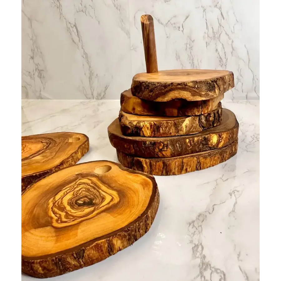 Stack of rustic olive wood cutting boards with natural bark edges and warm golden-brown tones.
