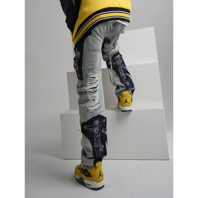 Distressed light-wash denim jeans featuring bold black panels with white line-art crucifixion designs and frayed, ripped details.