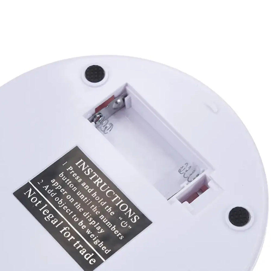 White circular electronic device with battery compartment and instructions label
