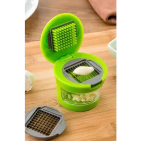 Green plastic garlic press with a clear glass base and interchangeable metal grater attachments.