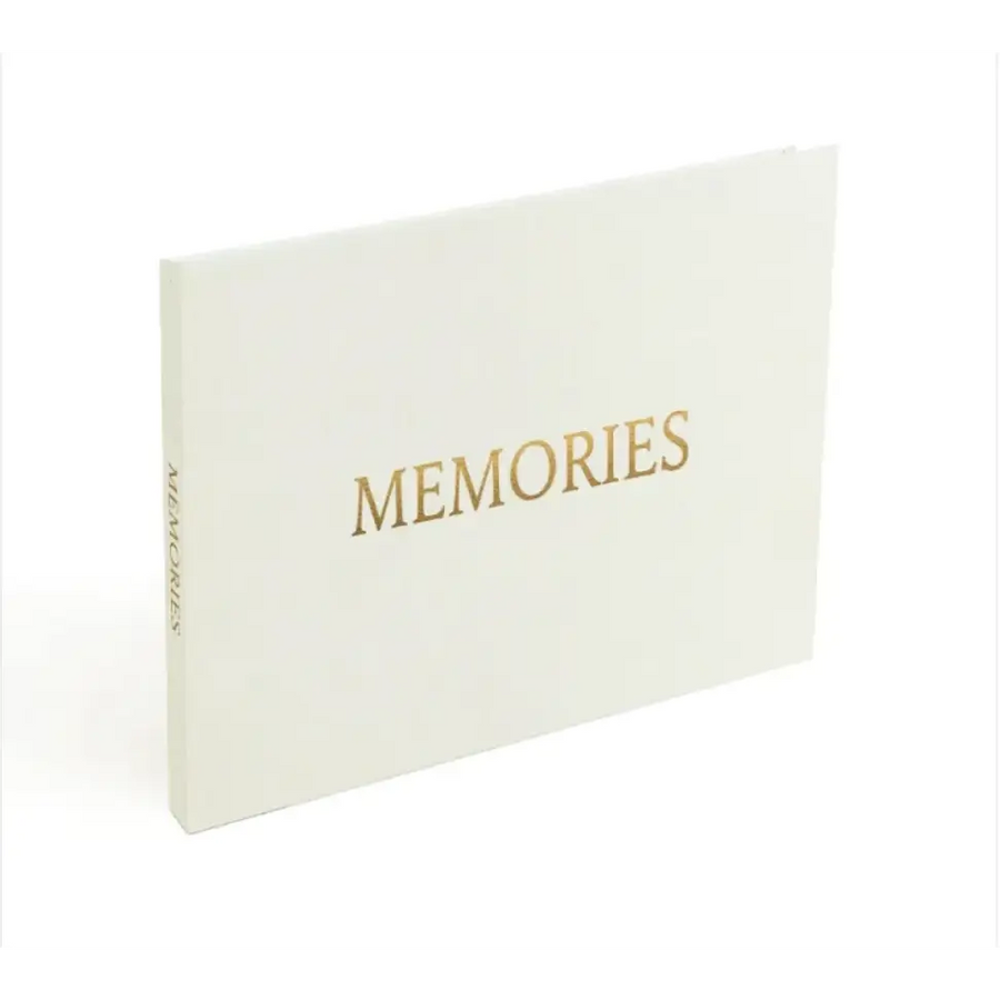 A cream-colored memory book with gold foil lettering that reads ’memories’ on the cover.
