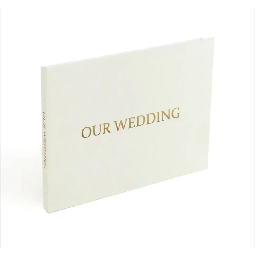 A minimalist white wedding album with elegant gold foil lettering that reads ’our wedding’ on the cover.