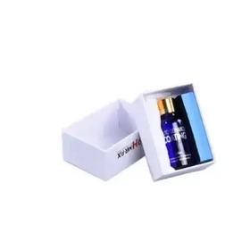 A sleek, dark blue glass bottle with a gold cap and white labeling sits inside an open white gift box.