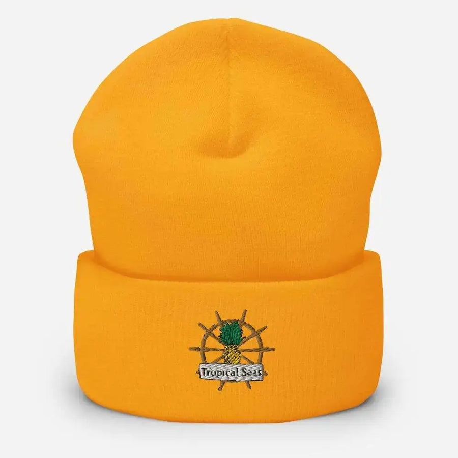 Bright orange knit beanie featuring an embroidered logo of a pineapple on a ship’s wheel with the text ’tropical seas’ beneath it.