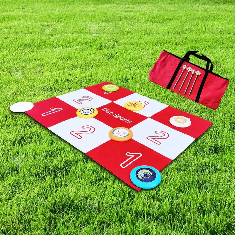 Red and white checkered disc sports disc golf target mat with colorful flying discs scattered across it.