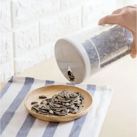 Clear plastic container with a white lid and a small spout, filled with dark gray sunflower seeds.