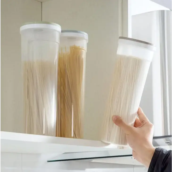 Clear plastic cylindrical storage containers with white lids, holding various types of dried pasta.