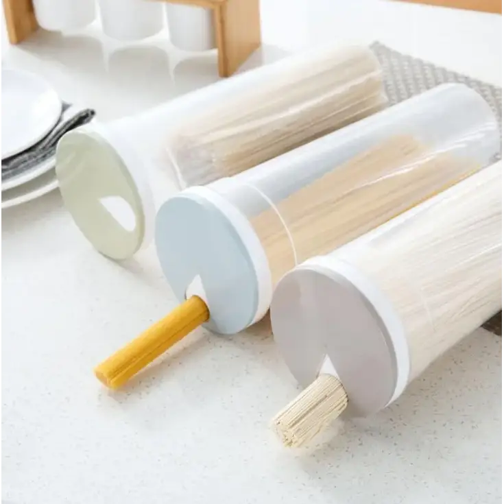 Three transparent cylindrical pasta storage containers with pastel-colored lids, each holding different types of noodles.