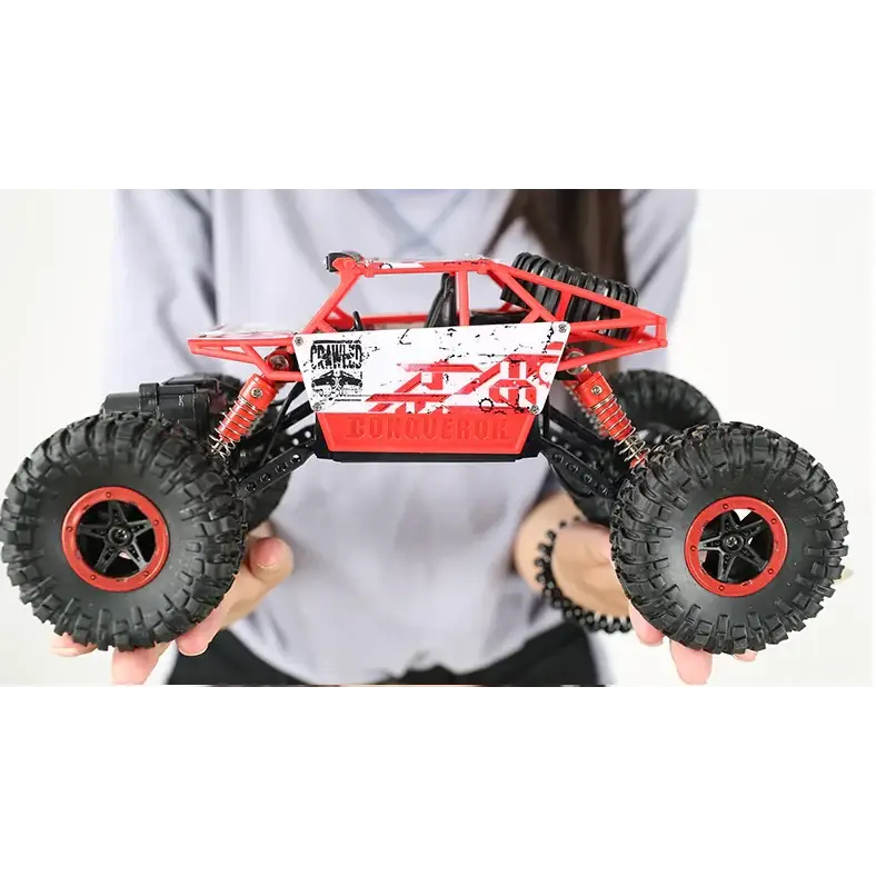 Red and white remote-controlled off-road truck with black rugged tires and red rims.