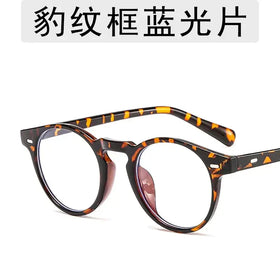 Round-framed glasses with a tortoiseshell pattern, featuring clear lenses and a sleek, modern design.