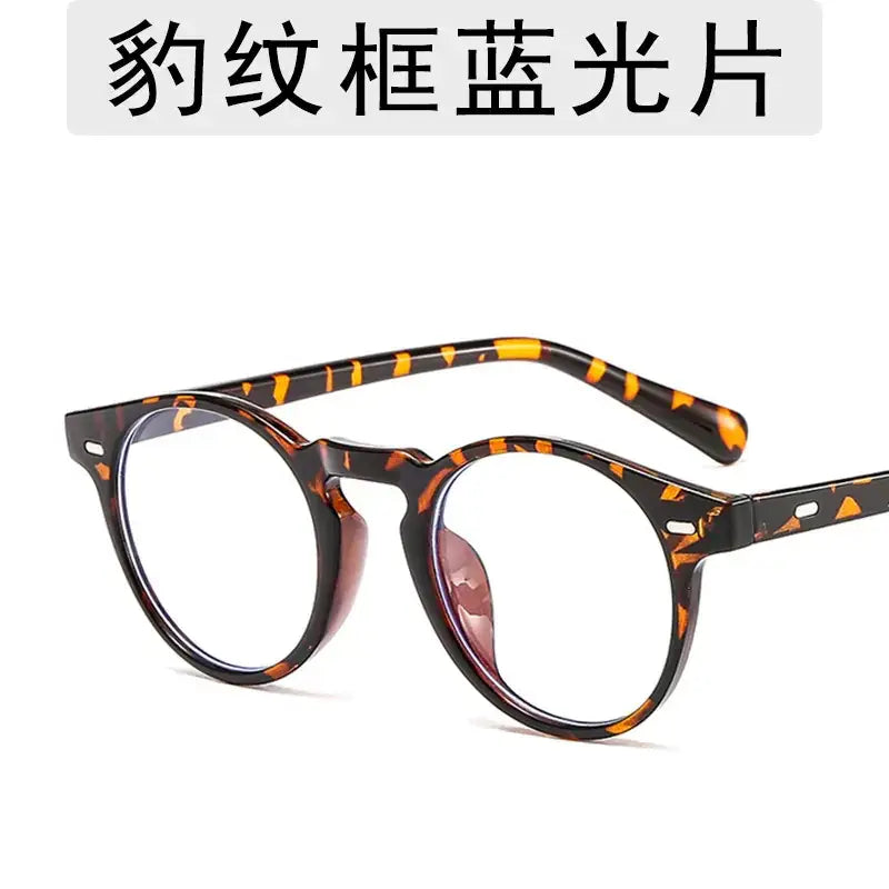 Round-framed glasses with a tortoiseshell pattern, featuring clear lenses and a sleek, modern design.