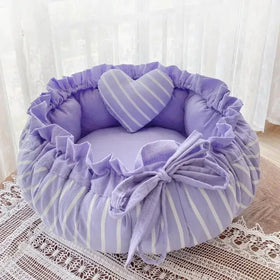 Lavender and white striped plush pet bed with ruffled edges and a matching heart-shaped pillow.