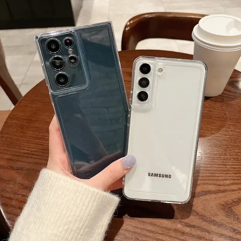 Two transparent phone cases, one in a dark blue hue and the other white, both featuring clear protective edges.