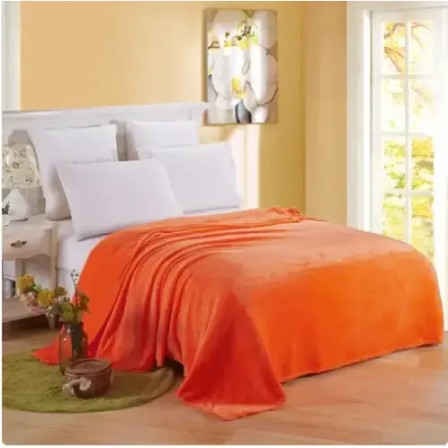 Bright orange plush throw blanket draped over a bed.