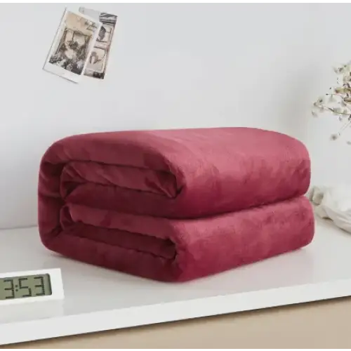 A plush, deep red fleece blanket neatly folded into a compact stack.