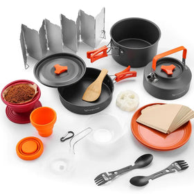 Black and orange portable camping cookset with foldable aluminum reflector, collapsible silicone cup, wooden spoon, and multi-tool utensils.
