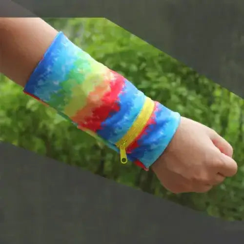 Rainbow tie-dye fabric wristband with a yellow zipper pull.