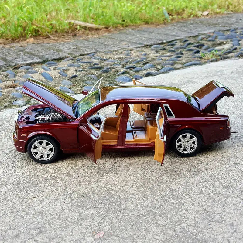 A detailed maroon diecast model of a rolls-royce phantom with all doors and the hood open, showcasing its intricate interior and engine.